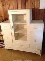 Front view of the white wooden china cabinet showing single glass door center section, two side wood doors, and three drawers.