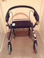 Front view of blue Dolomite Legacy Deluxe walker showing padded seat, basket, and padded hand grips.