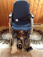 Front view of Quickie manual wheelchair with blue Obusforme cushions and removable footrests placed on the floor in front.