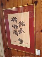 Framed print displayed against a wood-paneled wall