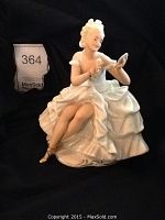 Angled frontal view of porcelain figurine showing detailed ruffled dress and facial expression