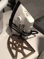 Proctor Silex iron with cord wrapped around, metal iron rest plate next to it