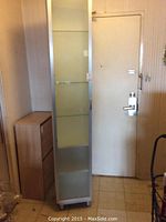 Closed view of the tall white IKEA cabinet with frosted glass door showing size and style.