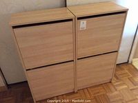 Pair of light wood IKEA cabinets shown closed, each with two horizontal drop-down front panels.