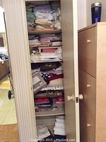 Closet shelving with various folded linens including bedding and towels