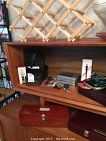 Wooden lattice wine rack and multiple boxed sets of bar tools and wine accessories on a wooden display shelf