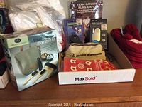 Photo of boxed travel shoe shine kit with other travel related items including light and dynamo flashlight and Canadian themed clothing items in a box.