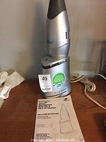 Photo of the Germ Guardian Clean rechargeable hand vac and UV-C air sanitizer unit on a wooden surface with power cord visible.