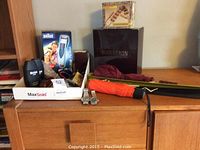 Overview of lot on wooden surface showing hair trimmer, fragrance boxes, knife tray, umbrellas, watches, shoe horns