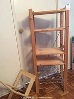 Wooden wine rack with metal wavy racks for wine bottles and two wooden shelves, along with a wooden magazine rack placed beside it.