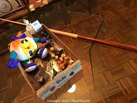 Photo showing box containing the wooden pool cue, plush 9 ball toy, and other items.