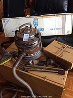 Filter Queen vacuum and accessories arranged on wooden floor in front of original boxes