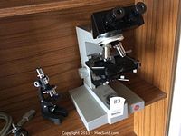 Wide view showing two microscopes and a power cord on shelf