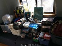 Wide shot of various bins, bags, and containers filled with sewing and knitting supplies and craft items on a bench.