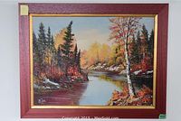 Full view of the framed oil painting showing autumn river landscape with fall foliage and rocky banks.