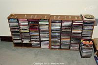 Two brown wood-grain CD stands loaded with CDs