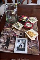 Photo of placemats with a rainy street scene, stacks of coasters featuring various prints, and a large clear glass jar.