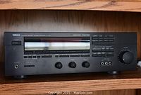 Front view of Yamaha RV901 stereo receiver showing control knobs and display panel on a wooden shelf.
