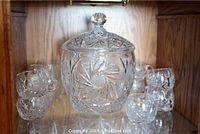 Crystal punch bowl with lid and 11 cups arranged on shelf showing overall condition
