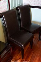 Front view of two brown faux leather chairs showing overall design and condition