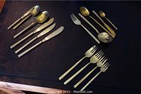 Complete assortment of flatware including knives, forks, spoons, and serving utensils arranged on table showing tarnish.