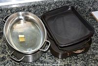 Large oval stainless steel roaster with handles on both sides, with butter inside.