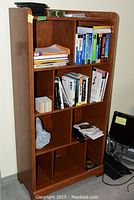 Full view of wooden bookcase showing various compartments with books and miscellaneous items placed on shelves.