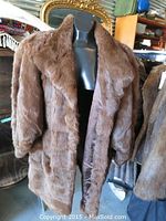 Front view of chocolate brown fur jacket on a mannequin showing fluffy texture and full sleeves.
