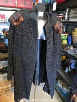 Front view of black Persian lamb coat with mink fur shawl collar on mannequin.