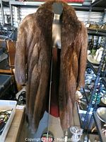 Front view of full-length brown fur coat on mannequin