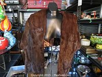 Brown mink fur stole displayed on a black mannequin. Visible are the soft, glossy fur exterior and the satin-like brown lining inside.