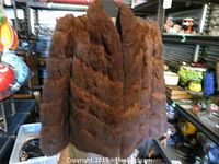 Front view of a brown fur jacket with chevron fur pattern on long sleeves and body