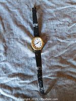 Full front view of watch showing case, dial, hands and leather strap with wear.