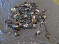 Pile of assorted sterling spoons laid out on fabric