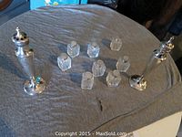 Full set of two tall sterling silver salt and pepper shakers with eight small cut glass shakers with silver tops on a gray cloth background.