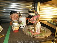 Shot of the two Beswick character mugs with hand-painted faces and Doulton and Falstaff mugs behind, including the black pitcher with pewter lid.