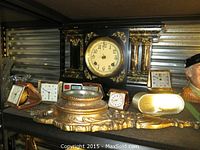 Shelf overview showing the black Seth Thomas mantle clock at rear and assorted small travel clocks in front