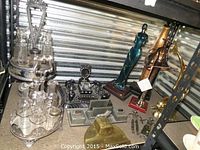 Overview of multiple desk sets and sculptures on shelf including cruet sets, inkwell set, metal organizer and figurines