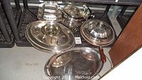 Overview of the silver plated serving trays and covered dish showing multiple items including trays and lidded serving dish