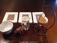 Wooden triple photo frame, elephant candle, decorative bowl, carved wooden elephant, metal hanging candle holder on a wooden surface