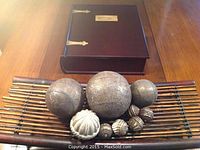 Top view of mahogany box closed with engraved brass plate, arranged decorative spheres and bamboo style wood tray beneath.