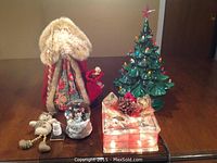 Photo showing the full lot with Father Christmas, ceramic Christmas tree, musical snow globe, glass block decoration, and small snowman figurine.