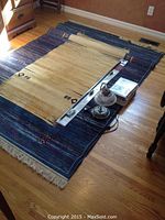 Photo showing the area rug, lamp, and flat-packed tab top curtain panels on a hardwood floor.