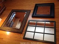 Three mirrors laid on wooden floor, showing different frames and styles