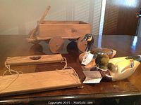 Wood carved duck decoys and wooden wagon displayed on table: two duck decoys and one wooden wagon pull toy with a handle.