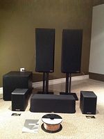 Full 5.1 system arranged including left/right speakers on stands, center channel, surrounds, subwoofer, wire and manual