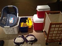 Lot including plastic laundry baskets, coolers, mesh bags, and a wooden hamper with fabric insert.