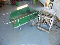 Overall view of the green garden cart next to white Suncrest hose reel with attached hose on the floor.