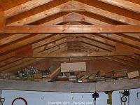 Wide view of the shed loft showing stacked lumber along the beam inside the roof space.