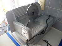 Front angled view showing food slicer platform, serrated blade, and thickness adjustment knob.